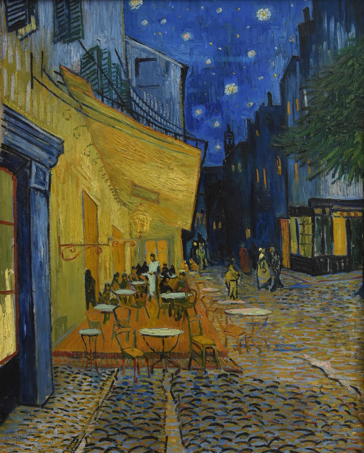 Cafe Terrace at Night by Vincent van Gogh, 1888 - a warm yellow lamplit terrace in Arles glows against a deep blue starry sky, people gathered at small tables